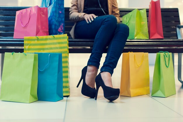 La section basse de la jeune femme avec des sacs à provisions au centre commercial