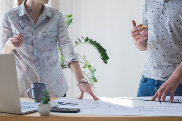 Photo gratuite section médiane d'un collègue travaillant sur un plan au bureau