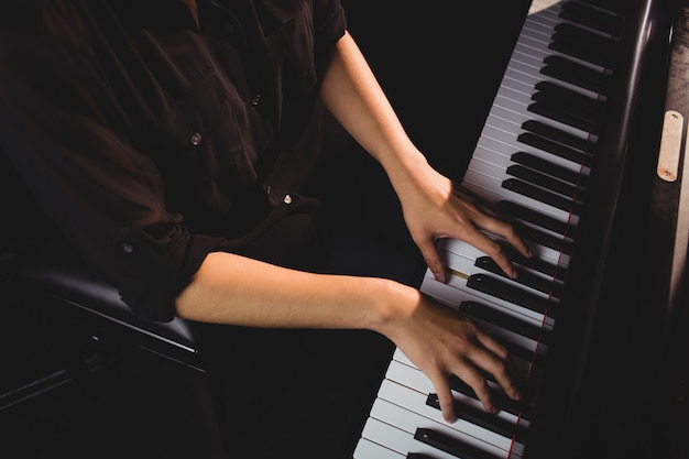 Photo gratuite section médiane d'une étudiante jouant du piano