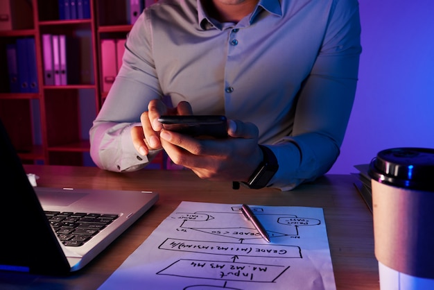 Section médiane d'un homme méconnaissable prenant une photo du plan de travail au téléphone