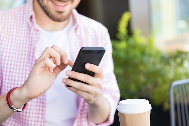 Section médiane d'un influenceur hispanique défilant des messages sur un smartphone au café