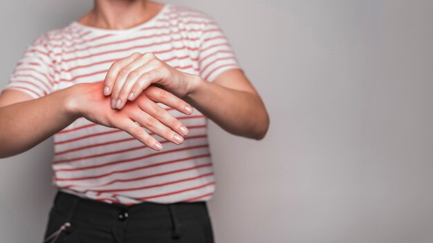 Section médiane d&#39;une jeune femme ayant des douleurs à la main sur fond gris