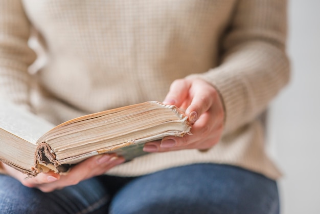 Section médiane de la main de la femme tenant un vieux livre ouvert