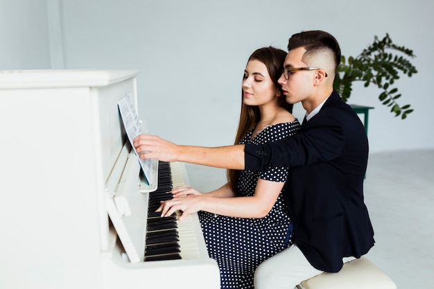 Un séduisant jeune couple jouant ensemble du piano
