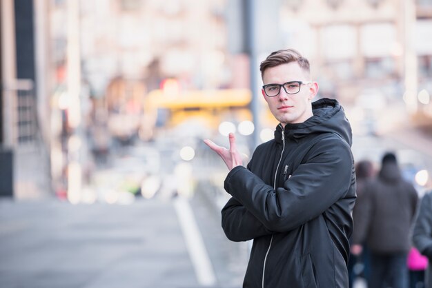 Un séduisant jeune homme debout sur la route en gesticulant