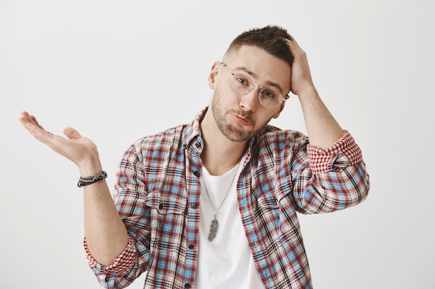 Séduisant jeune homme sombre avec des lunettes posant