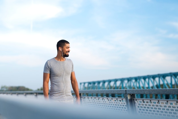 Séduisant sportif souriant et regardant de côté se préparant à courir