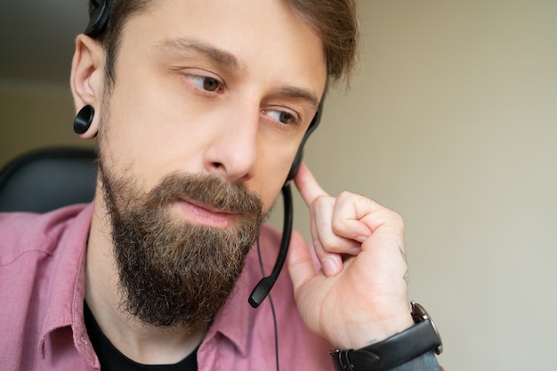 Séduisante jeune barbu travaillant avec casque