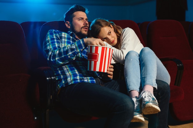 Séduisante jeune couple caucasien regardant un film dans un cinéma, une maison ou un cinéma. Ayez l'air expressif, étonné et émotif. S'asseoir seul et s'amuser. Relation, amour, famille, week-end.