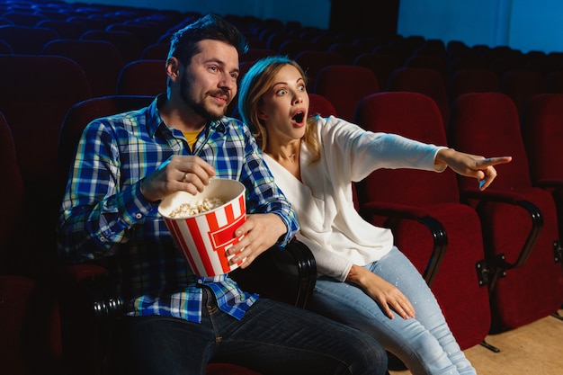 Séduisante jeune couple caucasien regardant un film dans un cinéma, une maison ou un cinéma.