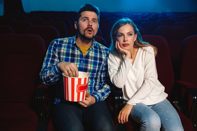 Séduisante jeune couple caucasien regardant un film dans un cinéma, une maison ou un cinéma.