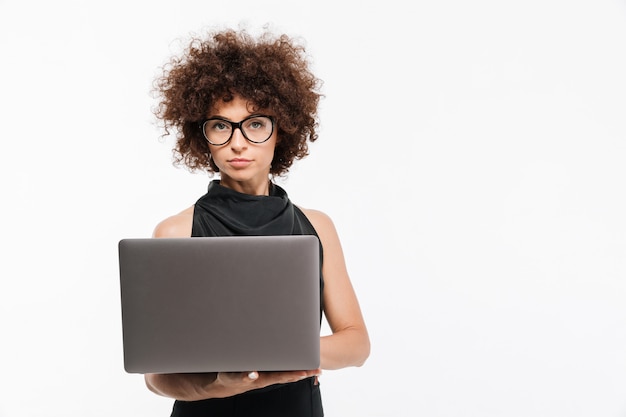 Séduisante jeune femme d'affaires à lunettes à l'aide d'un ordinateur portable