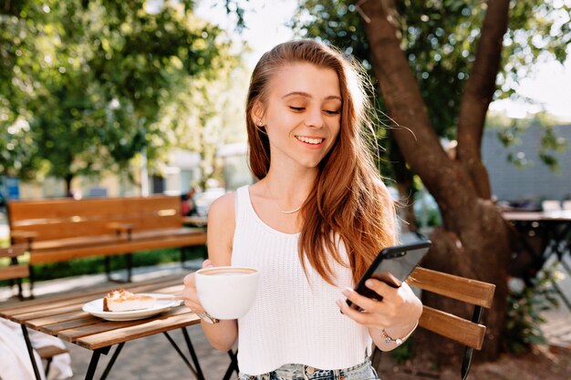 Séduisante jeune femme élégante hipster assise avec smartphone