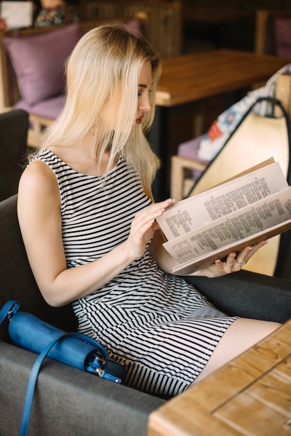 Séduisante jeune femme regardant menu assis dans le restaurant