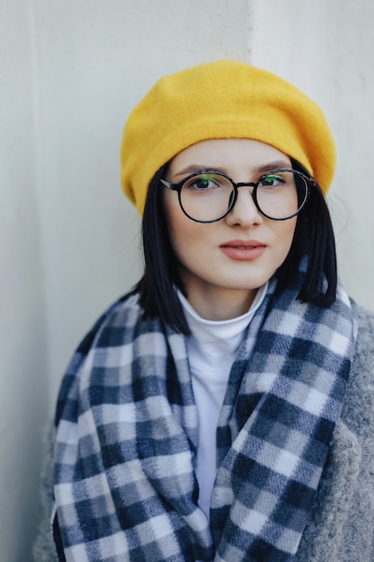 Photo gratuite séduisante jeune fille à lunettes en manteau et béret jaune