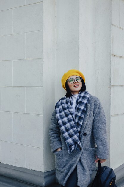 Séduisante jeune fille à lunettes en manteau et béret jaune