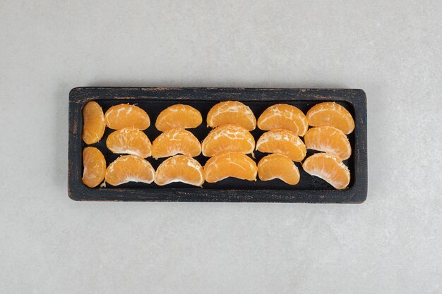 Segments de mandarine juteuse sur plaque noire