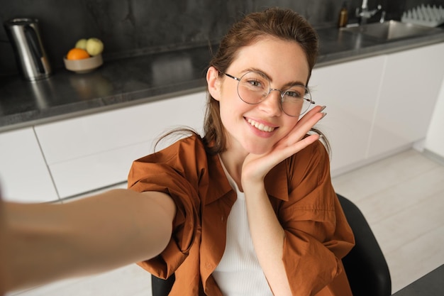 Selfie d'une jeune femme heureuse et insouciante prenant une photo sur un téléphone portable avec la main étendue posant et