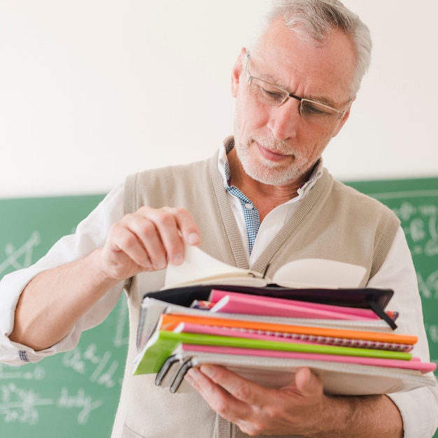 Senior enseignant vérifiant les bloc-notes en classe