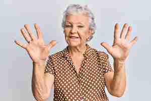 Photo gratuite senior femme aux cheveux gris portant des vêtements décontractés montrant et pointant vers le haut avec les doigts numéro neuf tout en souriant confiant et heureux