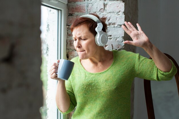 Senior femme chantant à la tasse de café