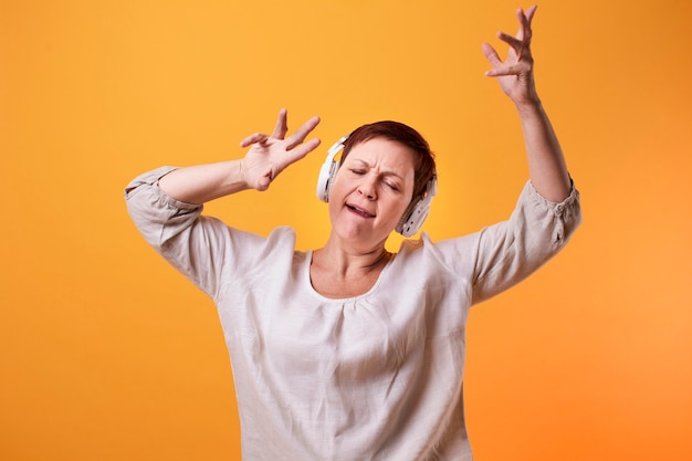 Senior femme danser et écouter de la musique sur des écouteurs