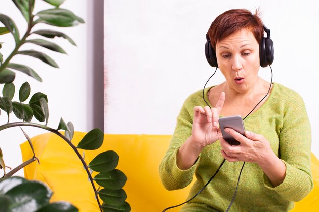 Senior femme étonnée écoutant de la musique