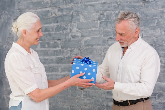 Senior femme offrant un cadeau d&#39;anniversaire à son mari