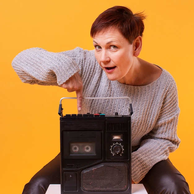 Photo gratuite senior femme vue de face tenant un lecteur de cassettes vintage