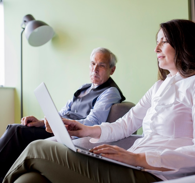 Senior homme d&#39;affaires en regardant une femme travaillant sur un ordinateur portable