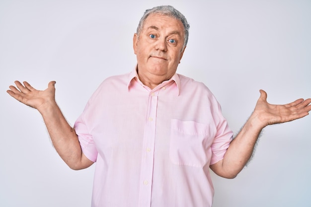 Photo gratuite senior homme aux cheveux gris portant des vêtements décontractés désemparés et confus avec les bras ouverts aucune idée et visage douteux