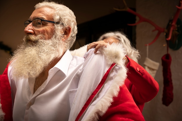 Senior homme à la barbe s'habillant en père Noël