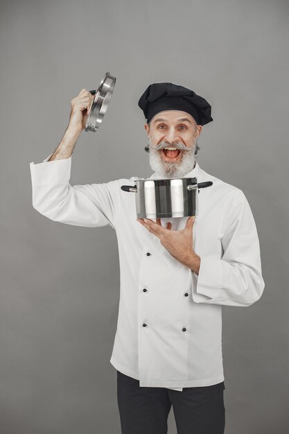 Senior homme avec casserole en métal. Chef dans un chapeau noir. Approche professionnelle des affaires.