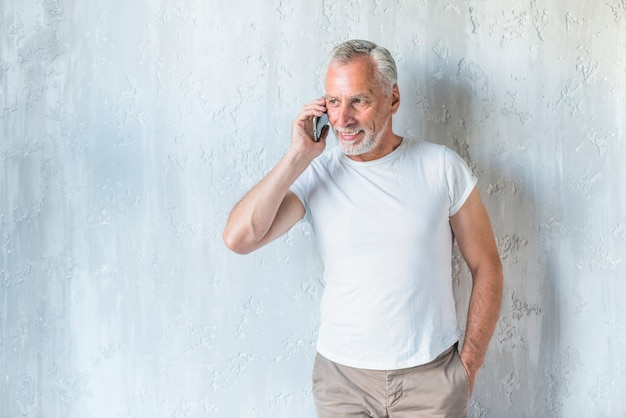 Senior homme avec les mains dans la poche, parler sur téléphone portable