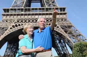 Photo gratuite senior homme montrant quelque chose à sa femme à côté de la tour eiffel