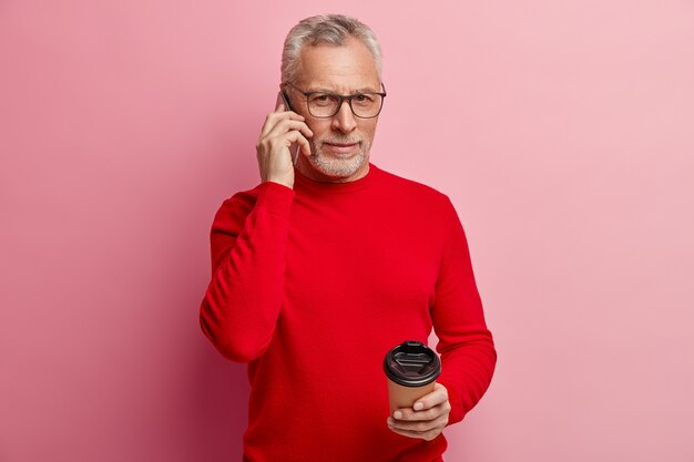 Senior homme portant un pull rouge et des lunettes à la mode