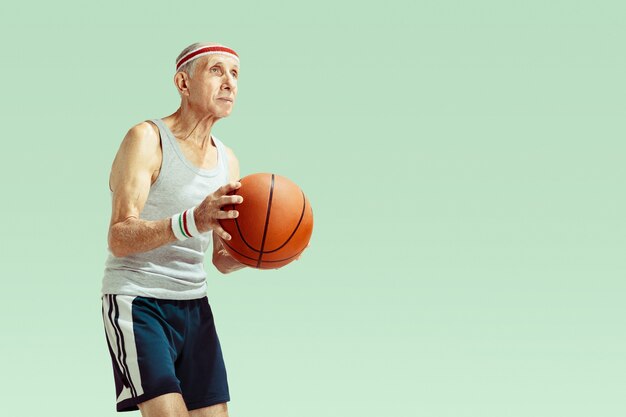 Senior homme portant des vêtements de sport jouant au basket sur vert