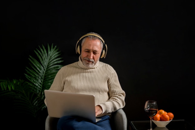 Senior homme en regardant un film près de mandarines et du vin