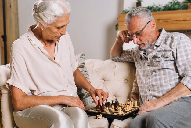 Senior homme regardant sa femme jouant aux échecs