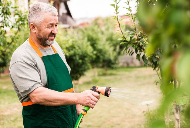 Senior homme avec tuyau d'arrosage