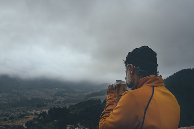 Senior male profitant de la vue tout en buvant un café sous un ciel maussade