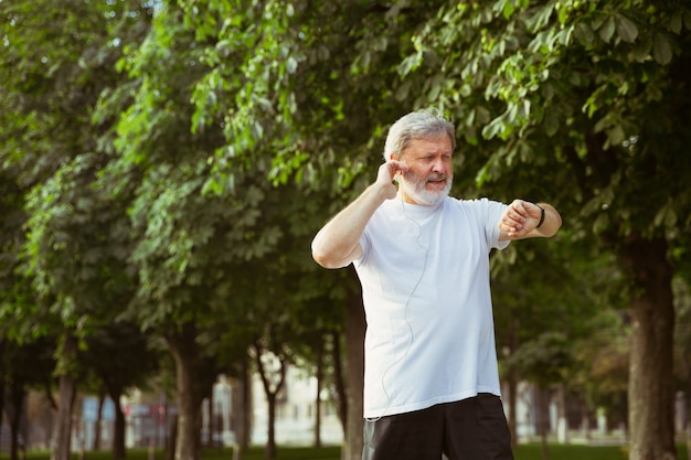 Senior man as runner avec fitness tracker à la rue de la ville