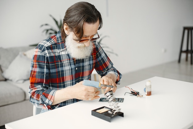 Senior man avec équipement pour la soudure. Travailler à la maison.