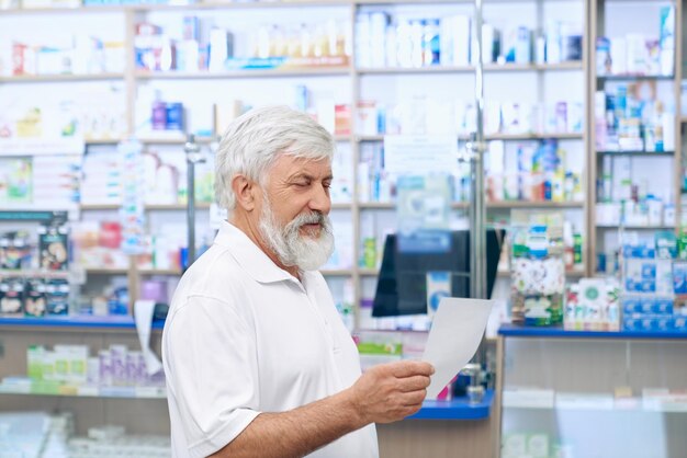 Senior man reading prescription en apothicaire