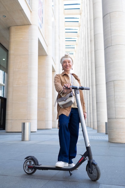 Senior woman posing avec un scooter électrique dans la ville