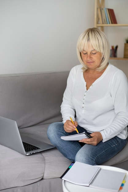 Senior woman prenant un cours en ligne sur son ordinateur portable à la maison