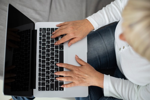 Photo gratuite senior woman prenant un cours en ligne sur son ordinateur portable à la maison