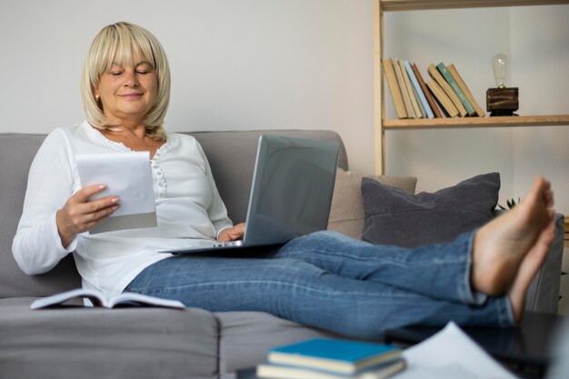 Senior woman prenant un cours en ligne sur son ordinateur portable à la maison