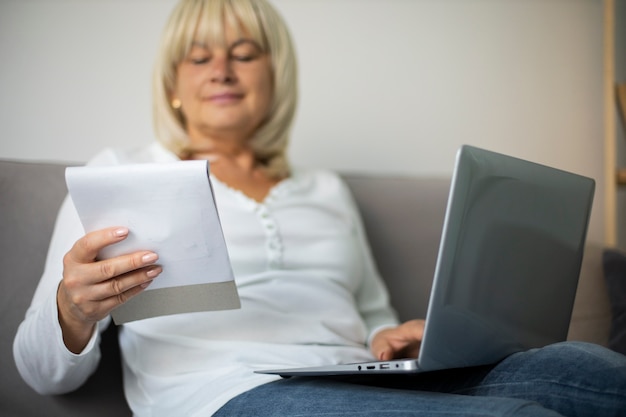 Senior woman prenant un cours en ligne sur son ordinateur portable à la maison