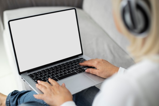 Senior woman prenant un cours en ligne sur son ordinateur portable à la maison